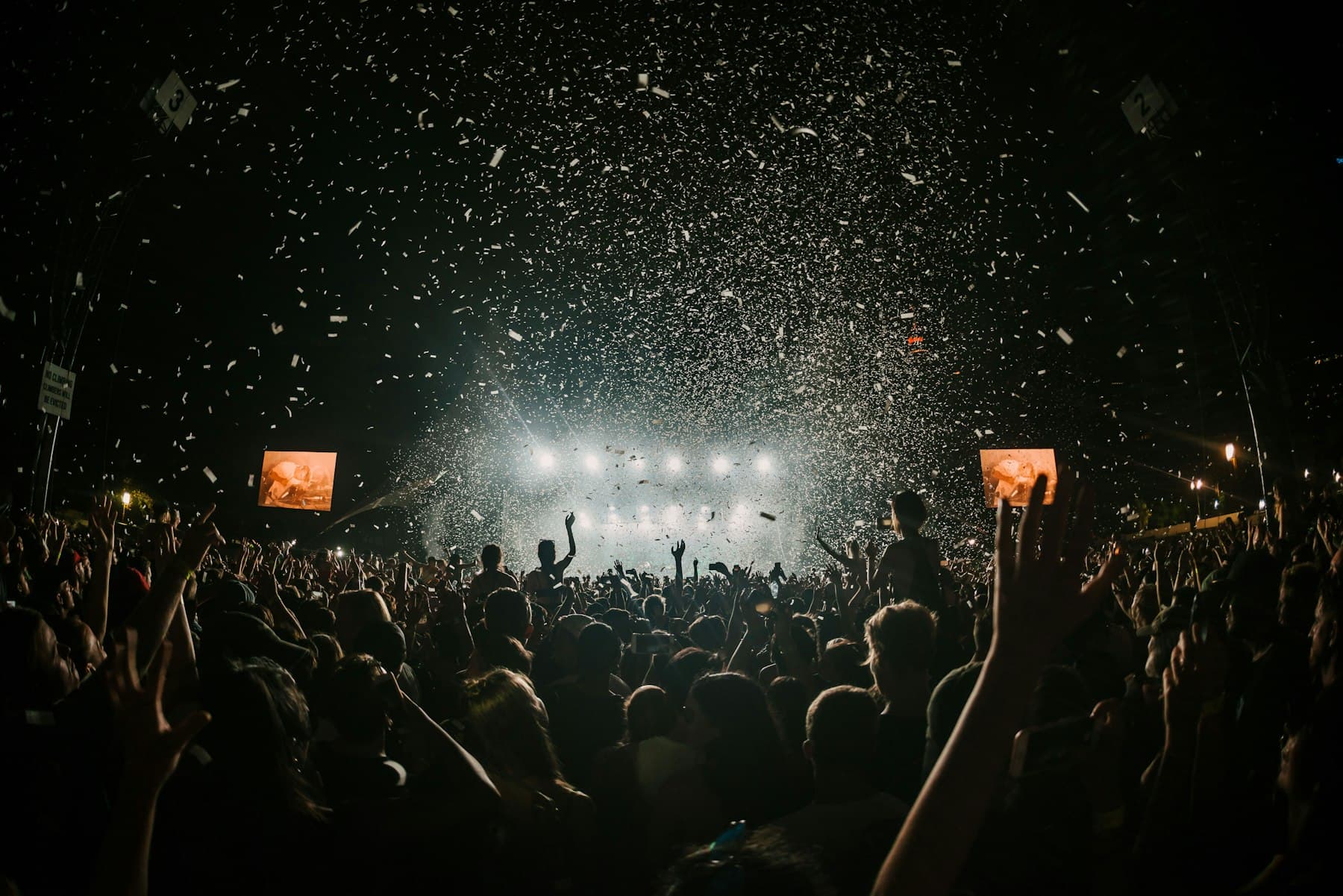 Chuva de confete caindo sobre a multidão em frente ao palco iluminado